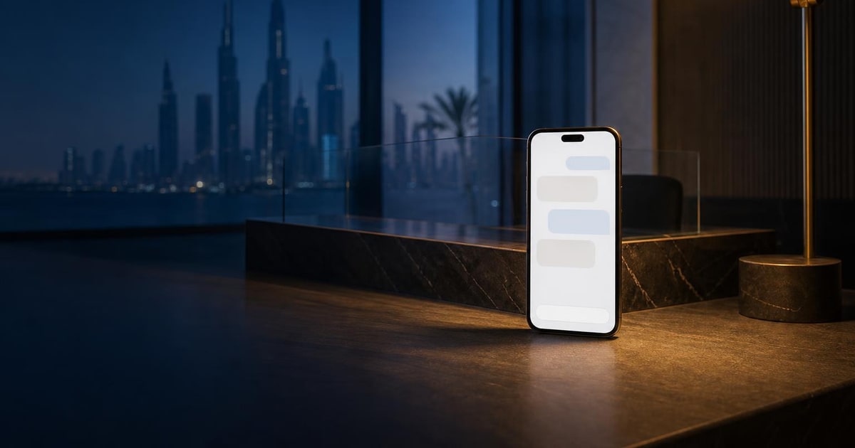 A smartphone rests on a support desk beside a service counter, lit by one warm lamp against a blue-hour office background.